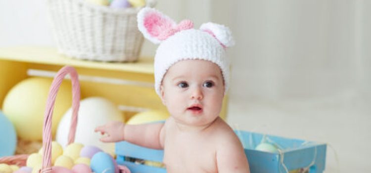 Cute little girl with Easter eggs sitting on floor at home.